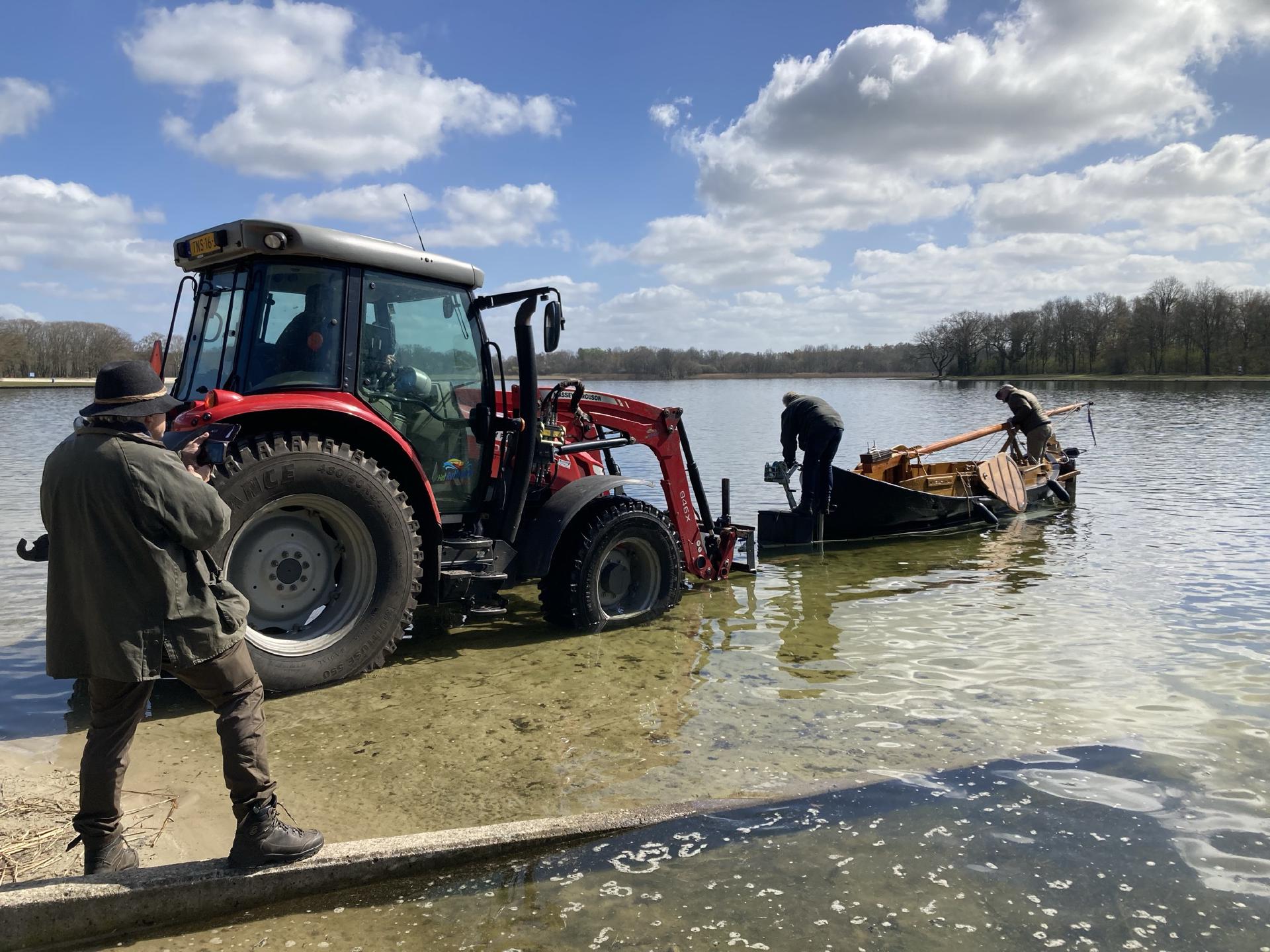 Een tractor die de Buurser Pot met een trailer in het water duwt bij het Rutbeek.