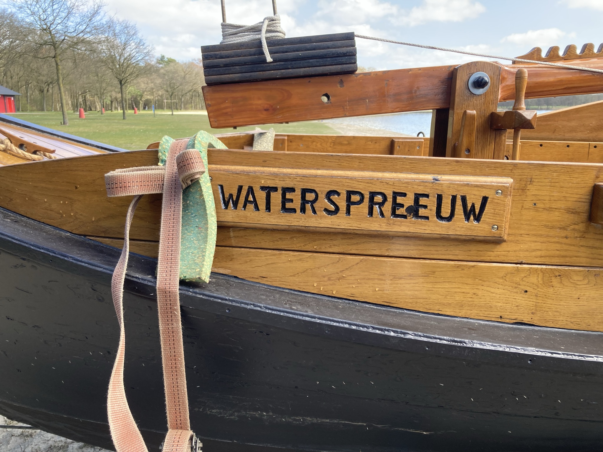 Close-up van de naam 'WATERSPREEUW' op de houten zijkant van de boot.