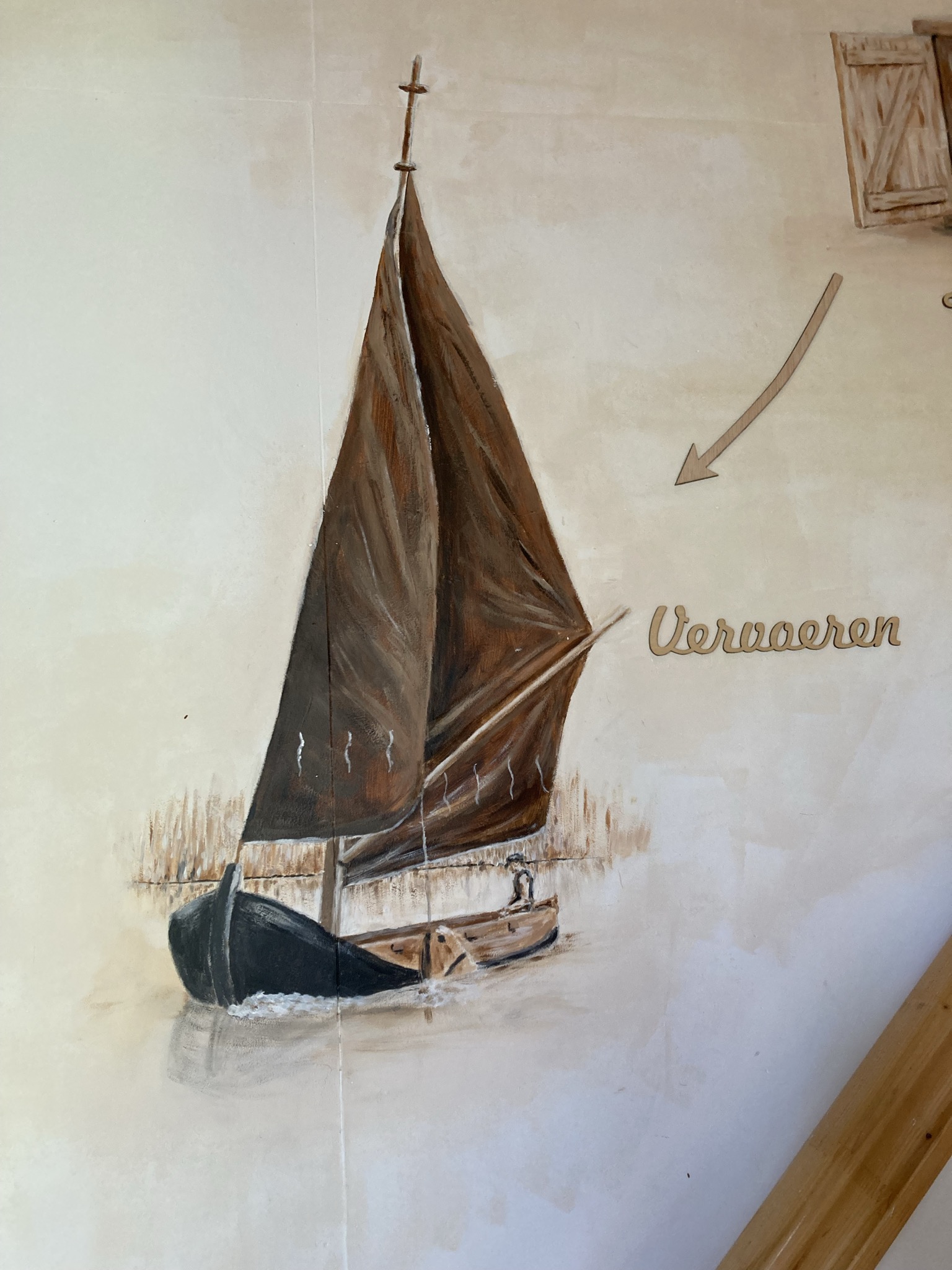 Een detail van een muurschildering waarop een zeilboot op het water te zien is met het woord 'Vervaeren' ernaast.